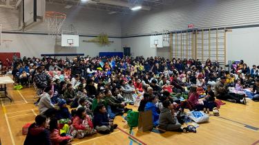 Students and families gathered in the school gym on the floor, ready to watch a movie