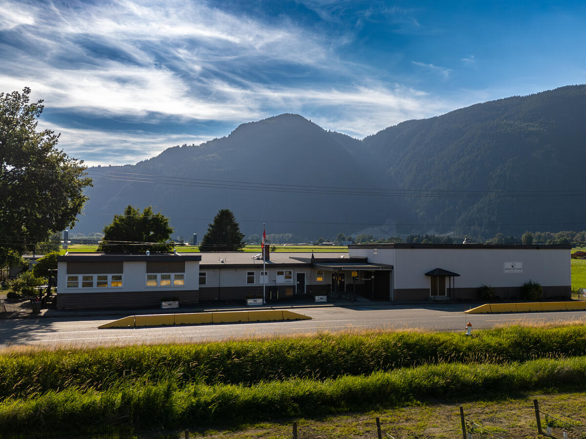 Exterior image of an elementary school located in the farm land. It has a view of a mountain and blue sky in the background.