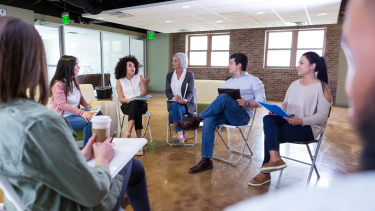 people sitting in chairs with clipboards talking